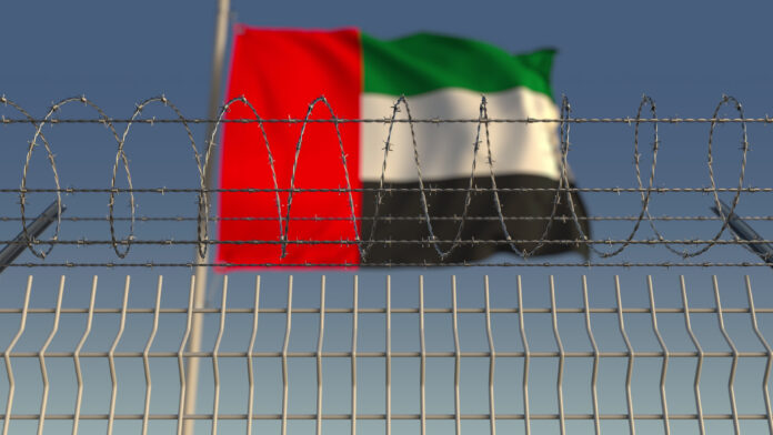 Barbed wire against waving flag of the UAE